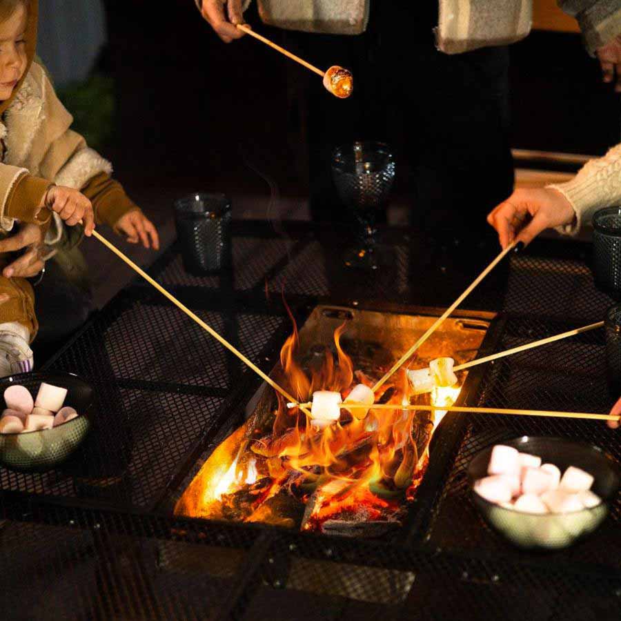 夜のキャンプで中央に火を灯したAroundFireを囲みマシュマロを焼く家族